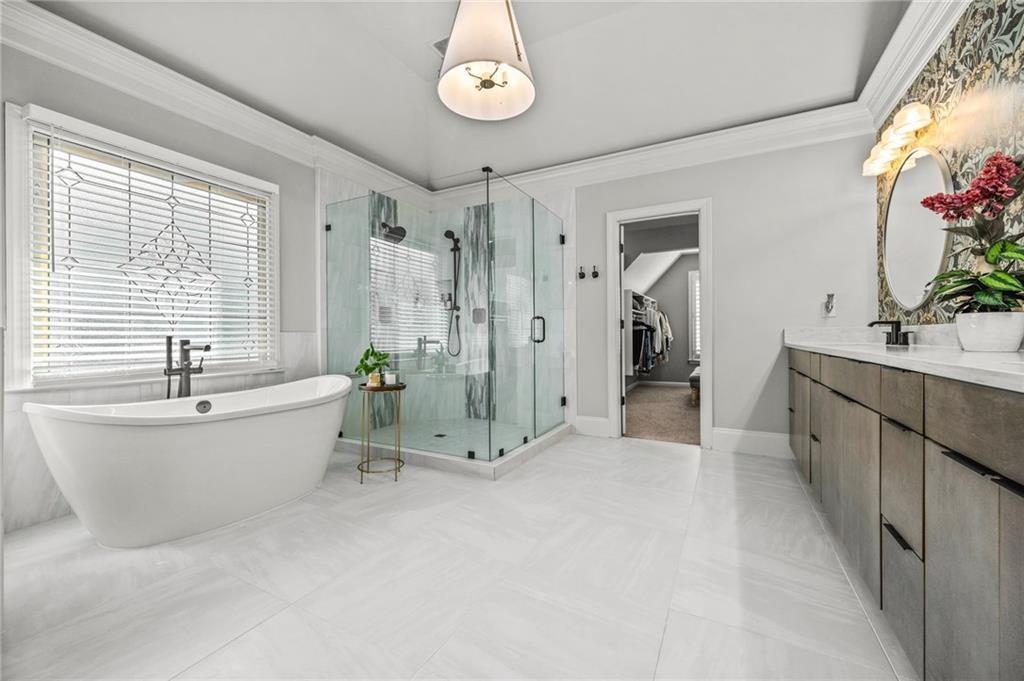 4526 Meadowland Way Flowery Branch, GA 30542 - Photo 28 of 64 a bathroom with a tub a sink and a large mirror