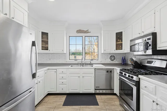 a kitchen with stainless steel appliances granite countertop white cabinets a sink dishwasher a stove and a refrigerator with wooden floor