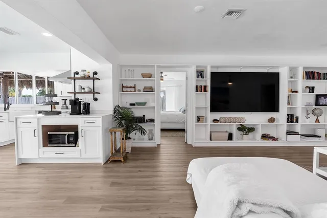 a kitchen with a stove oven and white cabinets with wooden floor