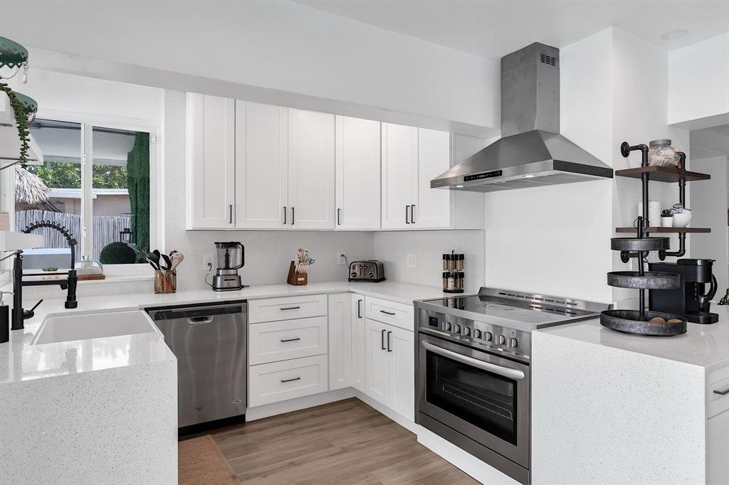 2233 Southeast 15th Street Pompano Beach, FL 33062 - Photo 29 of 53 a kitchen with stainless steel appliances granite countertop a sink stove and white cabinets