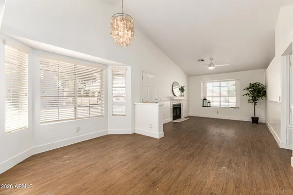 a view of an empty room with wooden floor and a fireplace