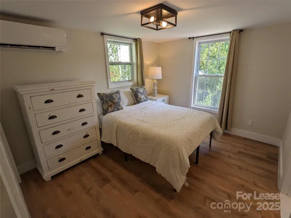 a bedroom with a bed a dresser with wooden floor