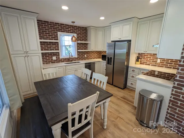 a kitchen with granite countertop a refrigerator a stove a sink dishwasher and wooden cabinets with wooden floor