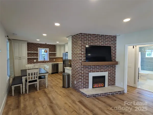 a living room with stainless steel appliances furniture a fireplace a flat screen tv and a fireplace