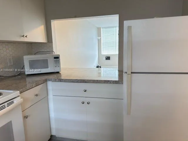 a bathroom with a granite countertop sink and white cabinets