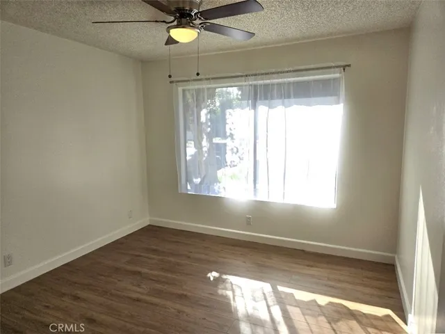 an empty room with wooden floor fan and windows