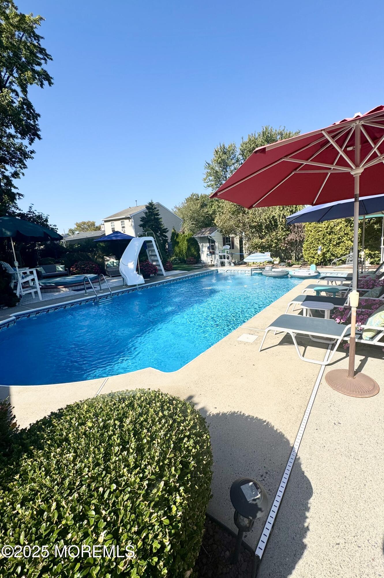902 10th Street Union Beach, NJ 07735 - Photo 30 of 37 a view of a swimming pool with lawn chairs under an umbrella