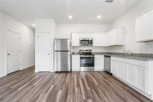 a kitchen with granite countertop a refrigerator oven a sink dishwasher and a stove with wooden floor