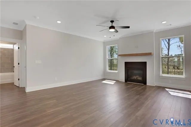 a view of an empty room with wooden floor fireplace and a window