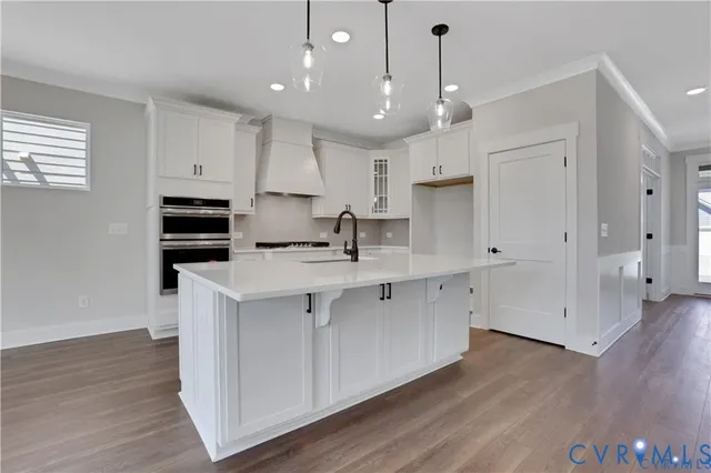 a large white kitchen with lots of counter space a sink appliances and cabinets