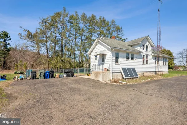 a view of a white house with a big yard and large trees