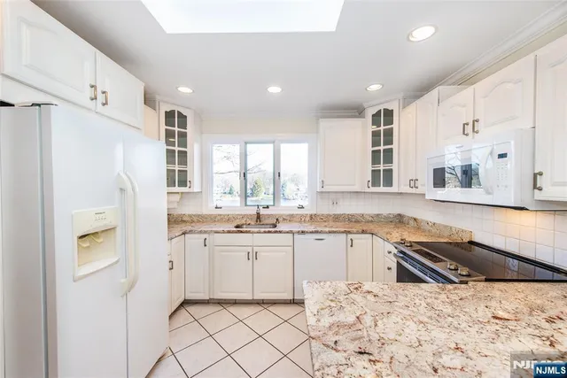 a large kitchen with granite countertop a sink and dishwasher a refrigerator with white cabinets