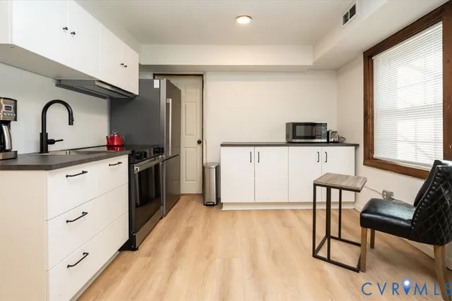 a kitchen with stainless steel appliances white cabinets and a refrigerator