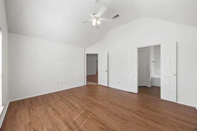an empty room with wooden floor and a ceiling fan