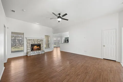 an empty room with wooden floor fireplace and windows