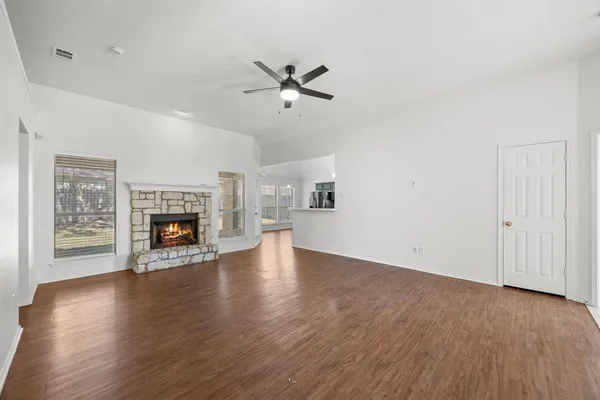 an empty room with wooden floor fireplace and windows