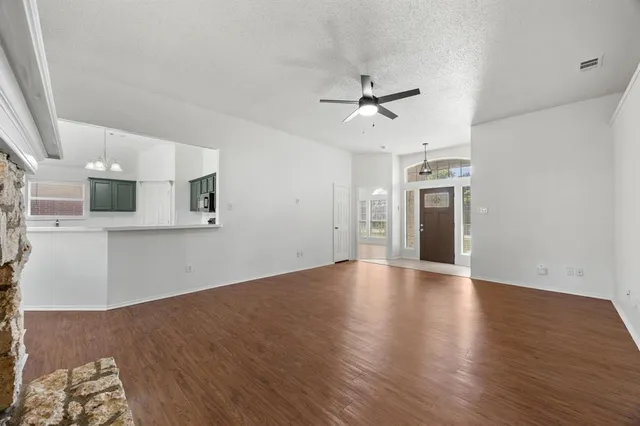 a view of empty room with wooden floor and ceiling fan
