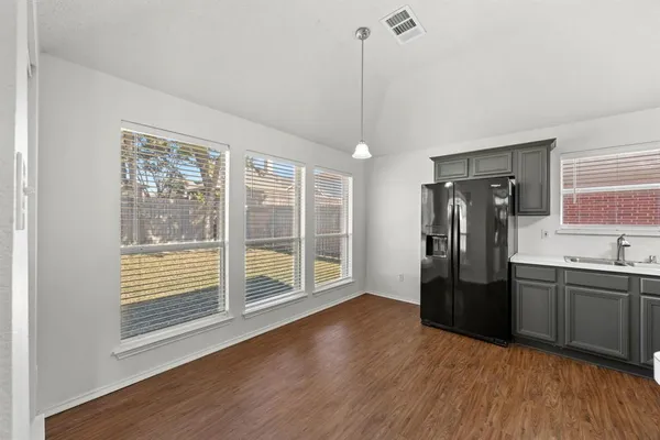 a kitchen with stainless steel appliances granite countertop a refrigerator a sink and wooden floors