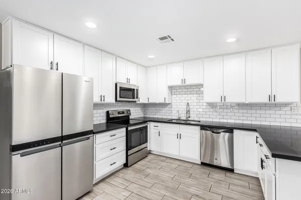 a kitchen with granite countertop a sink stainless steel appliances and cabinets