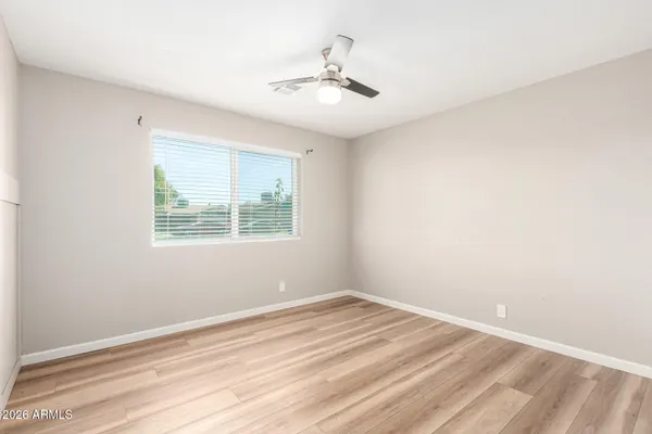 an empty room with a window and ceiling fan