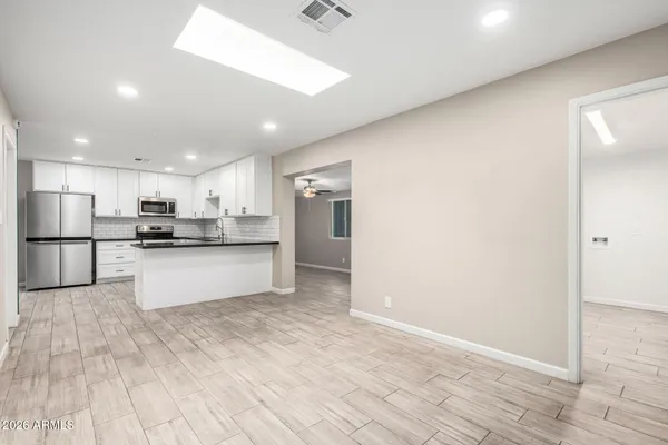 a large kitchen with kitchen island white cabinets and stainless steel appliances