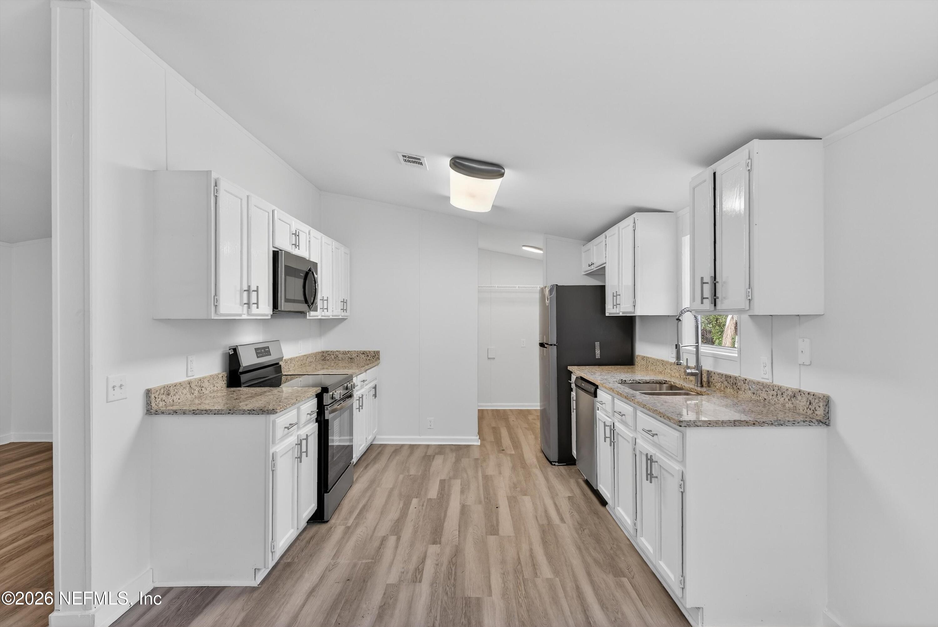 7595 Oak Forest Road Keystone Heights, FL 32656 - Photo 16 of 49 a kitchen with stainless steel appliances granite countertop a stove top oven a sink dishwasher and a refrigerator with wooden floor