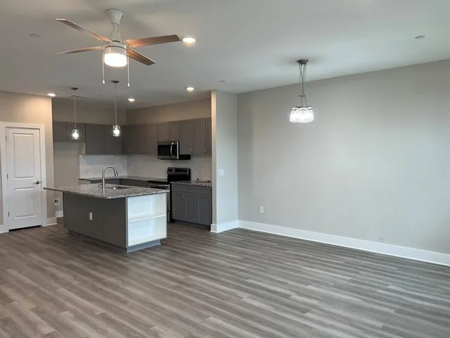 a large kitchen with granite countertop a large counter top a sink stainless steel appliances and cabinets