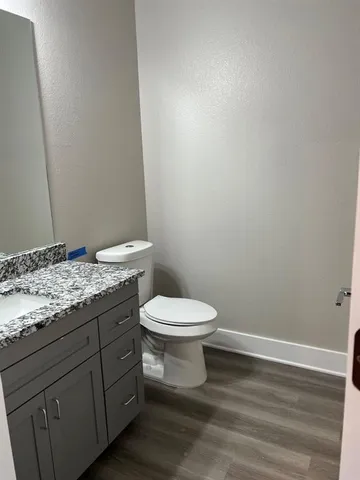 a bathroom with a granite countertop toilet and a sink
