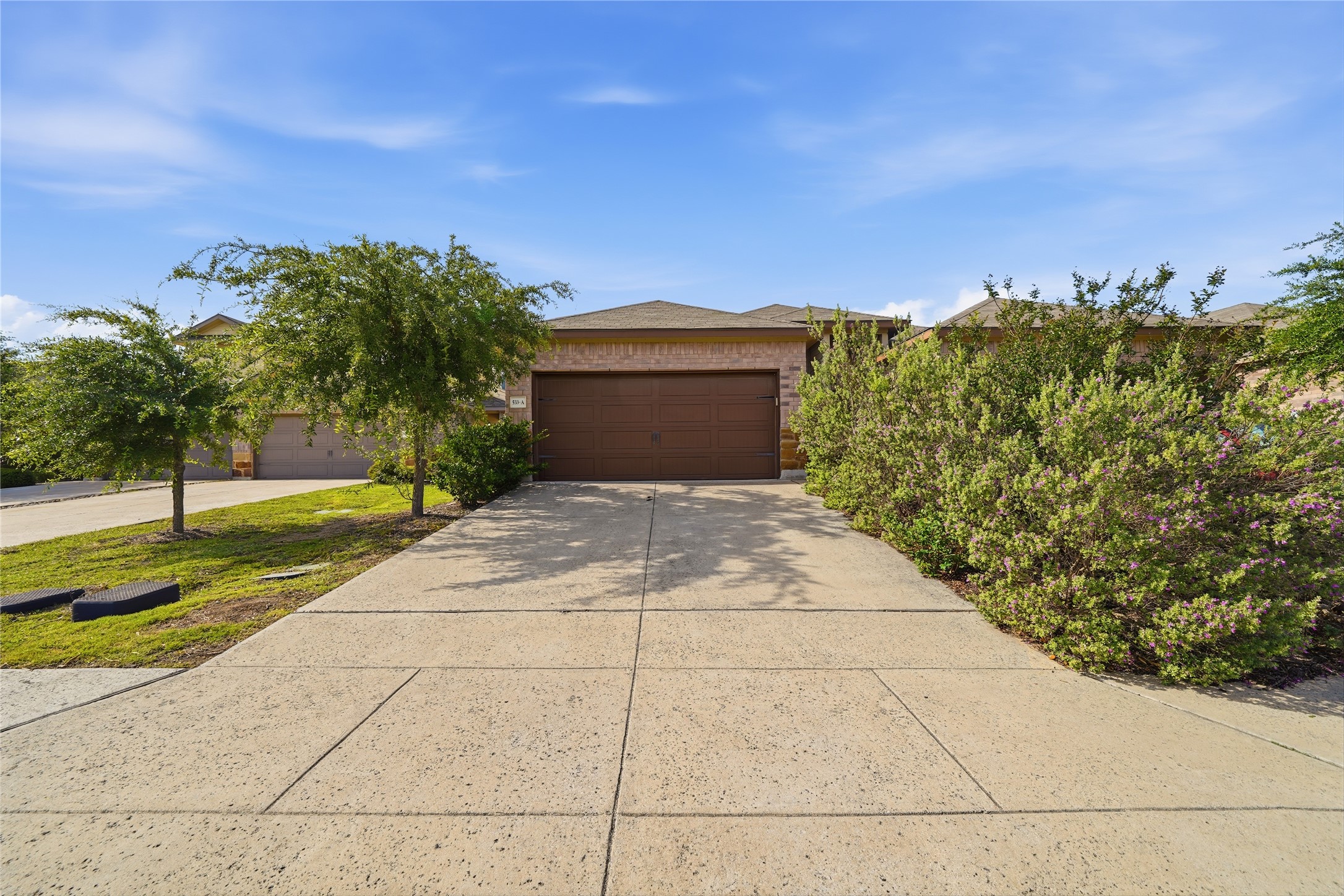 A well-maintained concrete driveway leads to a single-story residence with mature landscaping and an integrated garage.
