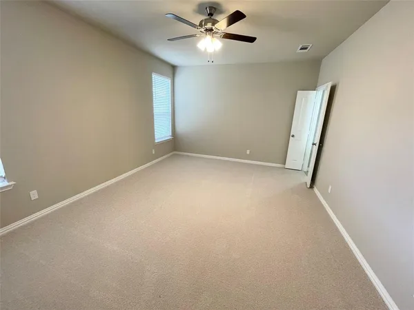 an empty room with a window and a fan