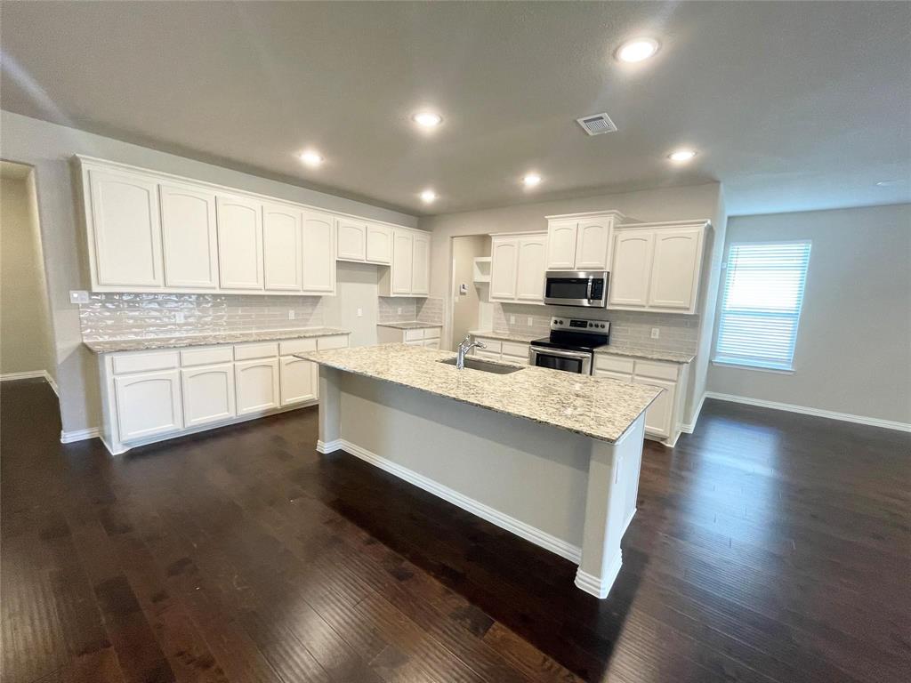 832 Porcupine Drive Springtown, TX 76082 - Photo 4 of 16 a kitchen with stainless steel appliances white cabinets a sink dishwasher a stove and a refrigerator with wooden floor