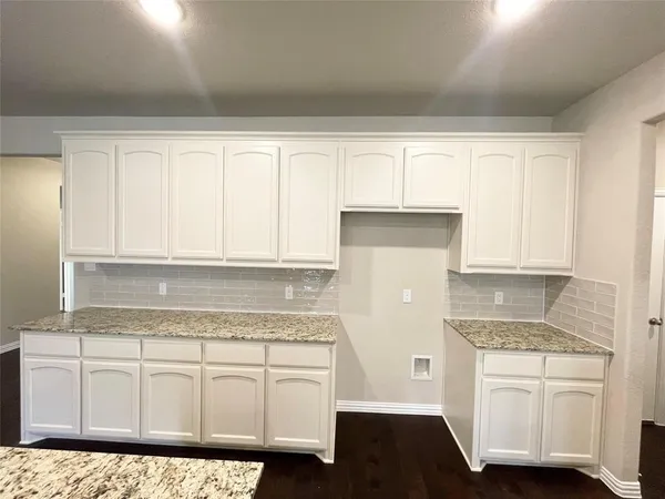 a kitchen with granite countertop white cabinets and white appliances