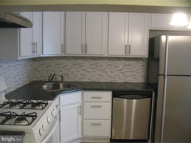 a kitchen with white cabinets and appliances