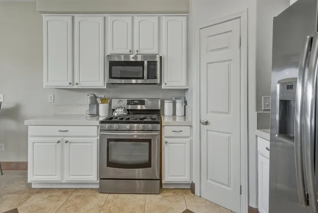 a kitchen with stainless steel appliances white cabinets and a stove top oven