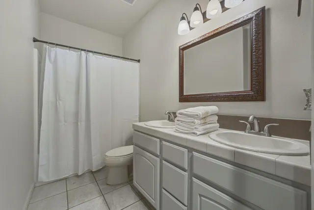 a bathroom with a granite countertop sink a toilet and a mirror