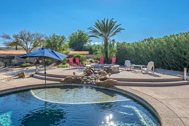 a view of a swimming pool with lawn chairs under an umbrella