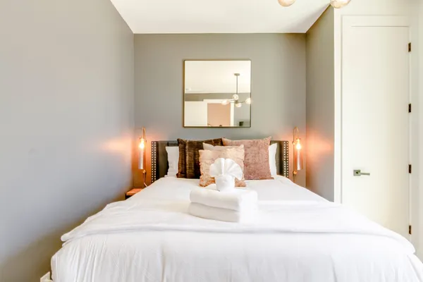 a large white bed in a room next to a lamp
