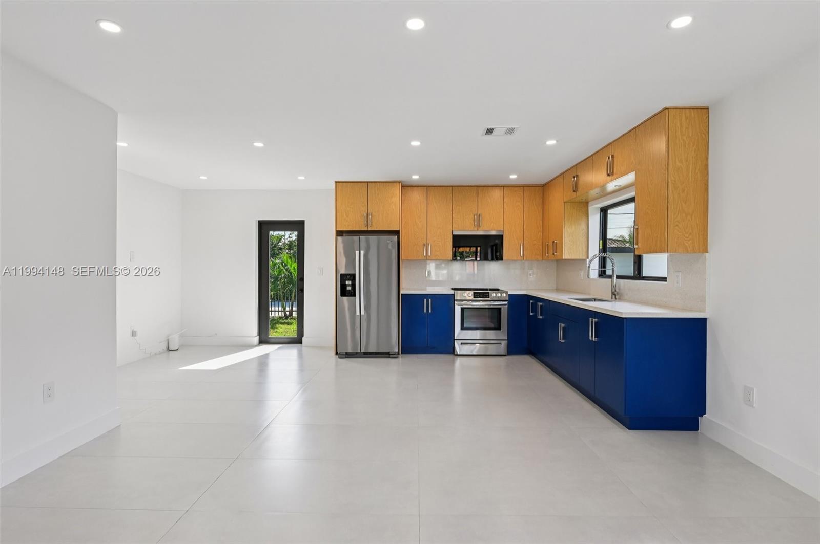 5152 Southwest 6th Street Miami, FL 33134 - Photo 35 of 43 a large kitchen with stainless steel appliances kitchen island granite countertop a stove a sink dishwasher and a refrigerator with wooden floor