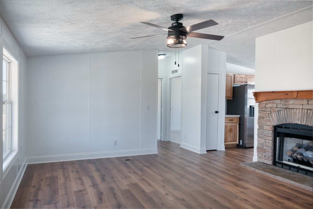 4214 Oregon Road Springfield, TN 37172 - Photo 10 of 37 an empty room with wooden floor a ceiling fan a fireplace and windows