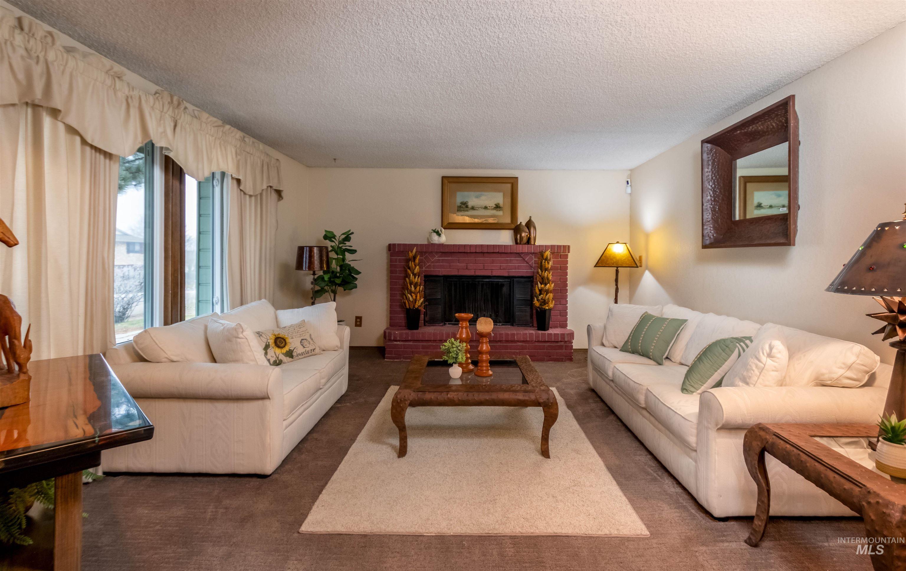 Living room featuring carpet, a fireplace, and a textured ceiling