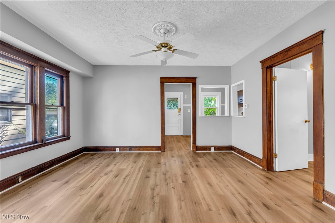 Spare room featuring light wood-type flooring, ceiling fan, and a textured ceiling
