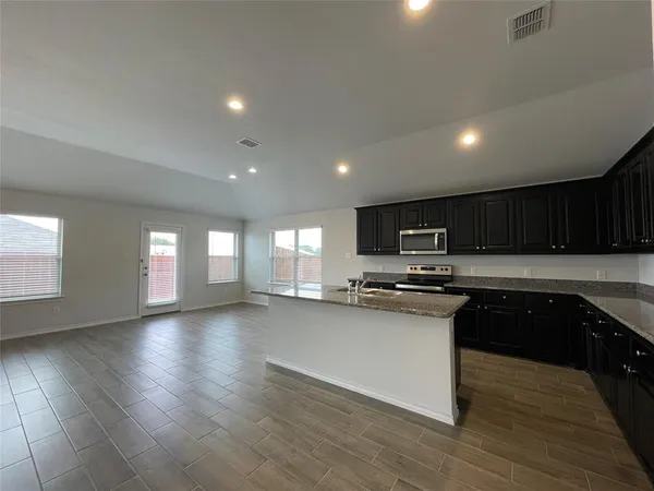 a kitchen with stainless steel appliances granite countertop a stove a sink a refrigerator and cabinets