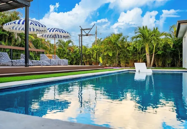 a dining area with stainless steel appliances kitchen island granite countertop a dining table chairs and a refrigerator