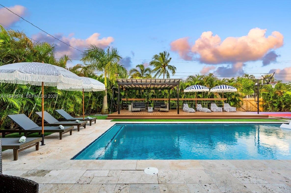5111 Adams Street Hollywood, FL 33021 - Photo 9 of 66 a view of a swimming pool with lawn chairs under an umbrella