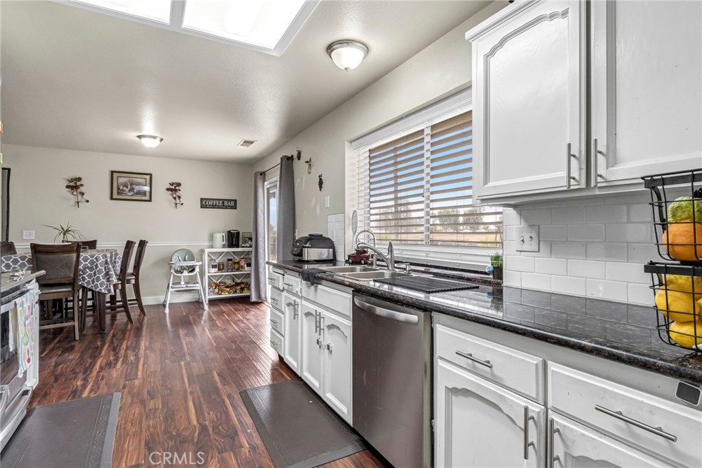 19729 Brightwood Road Madera, CA 93638 - Photo 14 of 33 a kitchen with stainless steel appliances granite countertop a stove a sink and white cabinets with wooden floor