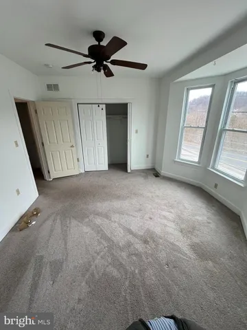 an empty room with ceiling fan and windows