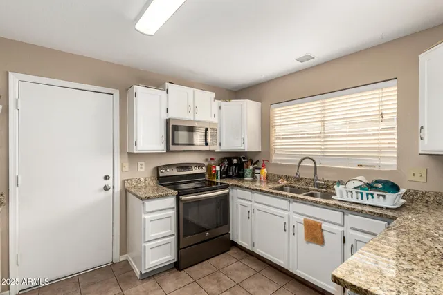 a kitchen with stainless steel appliances white cabinets a sink a stove a refrigerator and cabinets