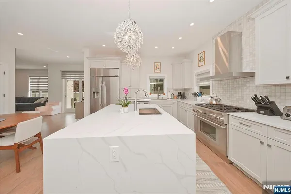 a large white kitchen with kitchen island a sink stainless steel appliances and cabinets