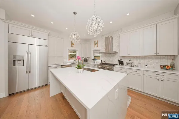 a kitchen with kitchen island white cabinets and stainless steel appliances