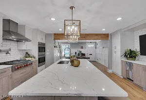 a kitchen with stainless steel appliances granite countertop a stove a refrigerator a sink and white cabinets